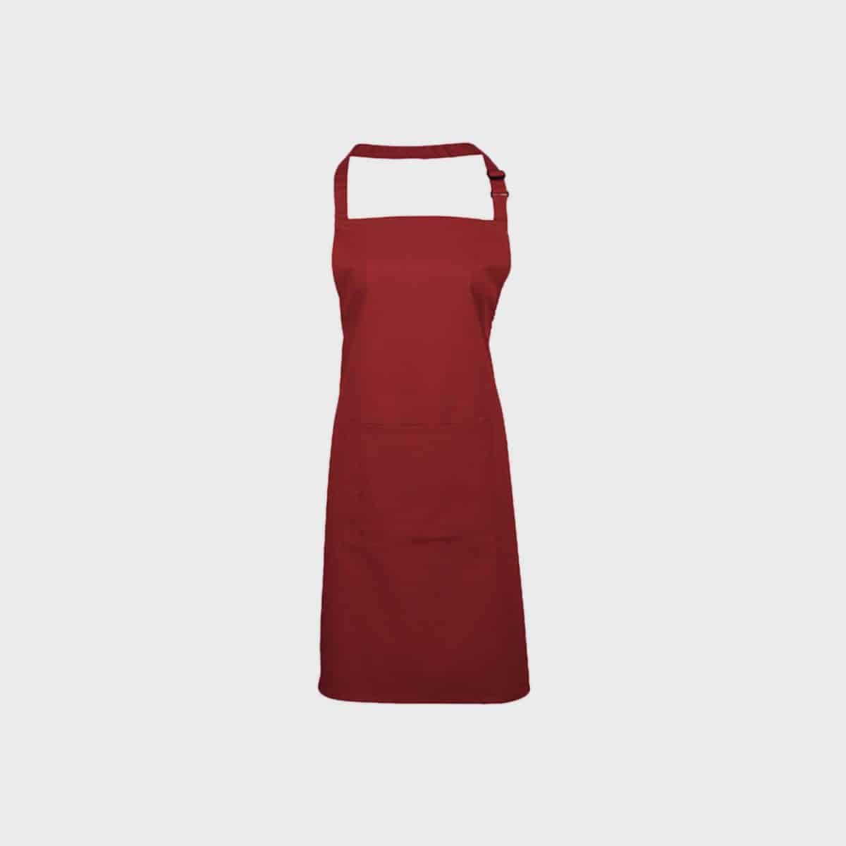 Eine Vorderansicht einer schlichten, roten Latzschürze von PREMIER WORKWEAR mit Nackenband und Taillenbändern, dargestellt vor einem weißen Hintergrund. Diese Küchenschürze hat ein schlichtes Design ohne sichtbare Taschen oder Muster.