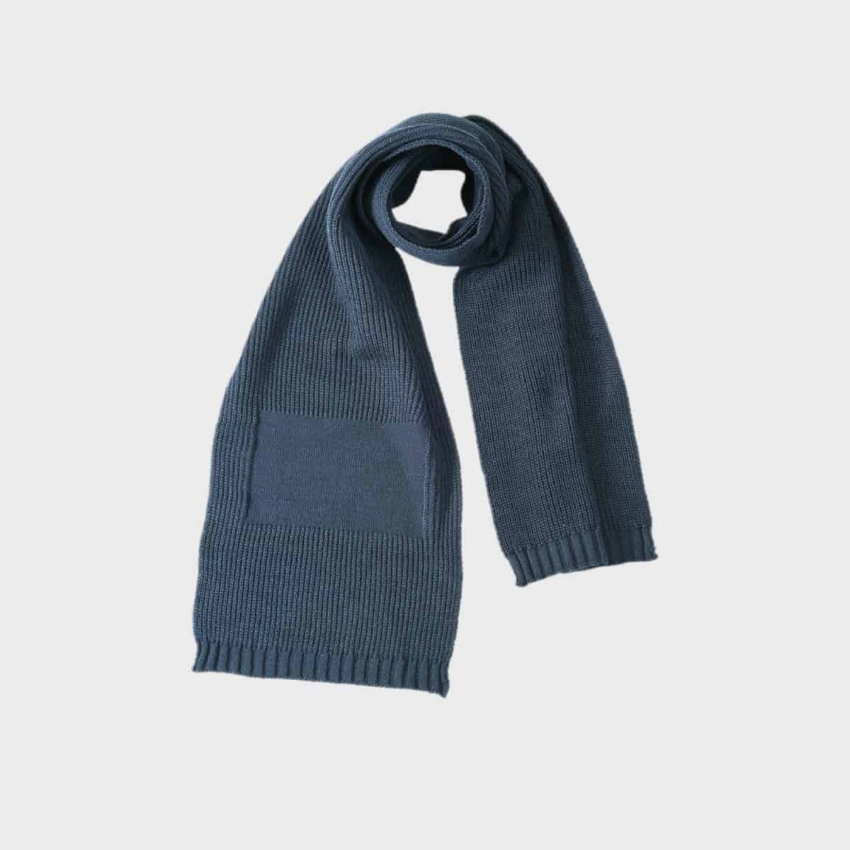 Ein sauber gefalteter Werbeschal mit dunkelblauem Strickdesign mit gerippten Kanten und rechteckigem Flickenmuster an einem Ende vor einem schlichten weißen Hintergrund, perfekt für jede Modewerbung.