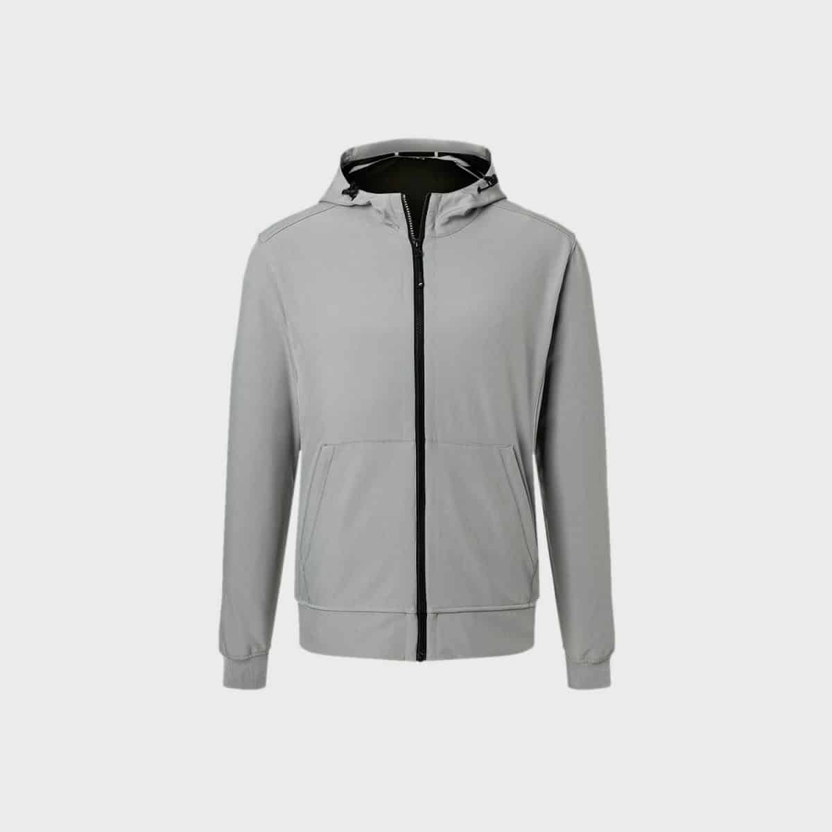 Die Herren-Softshelljacke mit Kapuze ist in Grau gehalten, hat einen schwarzen Reißverschluss auf der Vorderseite und zwei große Taschen. Die Ärmel sind mit elastischen Bündchen ausgestattet und die Kapuze verfügt über Kordelzüge zur Anpassung. Dieser minimalistisch gestaltete Hoodie wird vor einem schlichten weißen Hintergrund präsentiert.