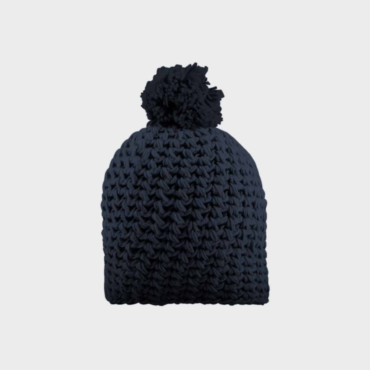 Eine grob gestrickte dunkelblaue Beanie-Mütze mit einem großen Bommel oben drauf. Die Struktur des Stricks ist deutlich sichtbar und verleiht ihr ein gemütliches und warmes Aussehen. Der Hintergrund ist schlicht und hellgrau, wodurch die Mütze deutlich hervorsticht.