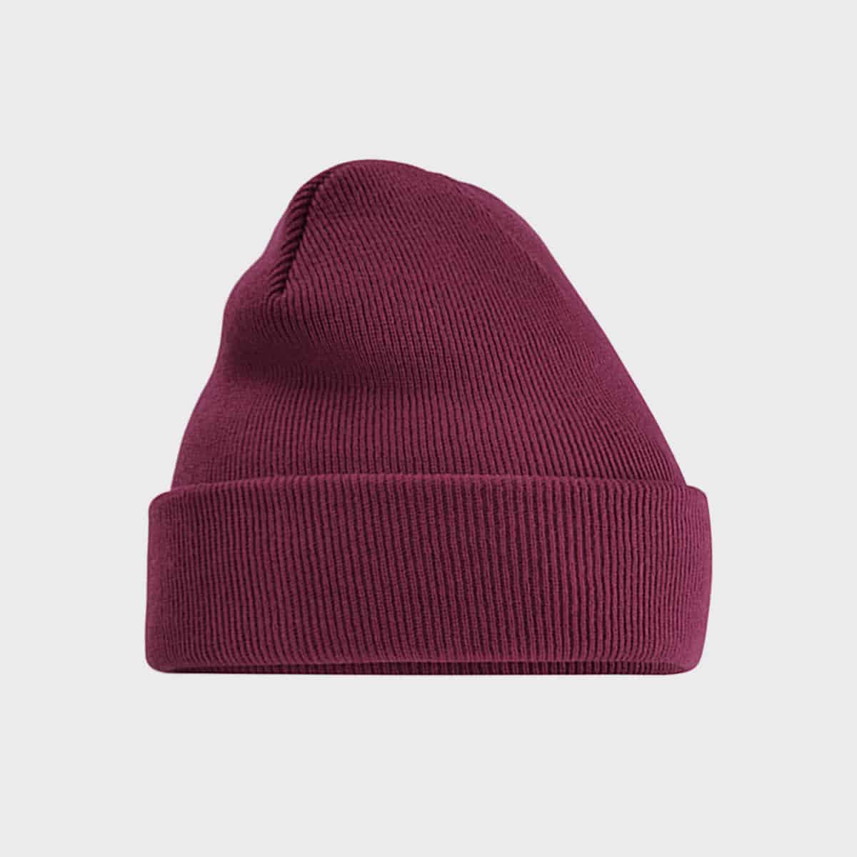 Eine kastanienbraune gerippte Beanie-Mütze mit umgeschlagenem Bündchen steht zentriert vor einem schlichten weißen Hintergrund. Die Textur des Strickstoffs ist sichtbar und sorgt für ein gemütliches und lässiges Aussehen.